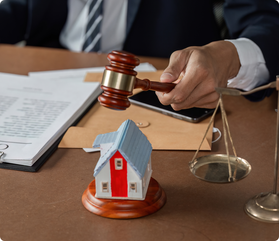Gavel and scales near house model on desk.